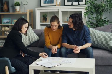 pexels-photo-23225013-23225013-1 A real estate agent discusses house plans with a couple in a modern living room setting.
